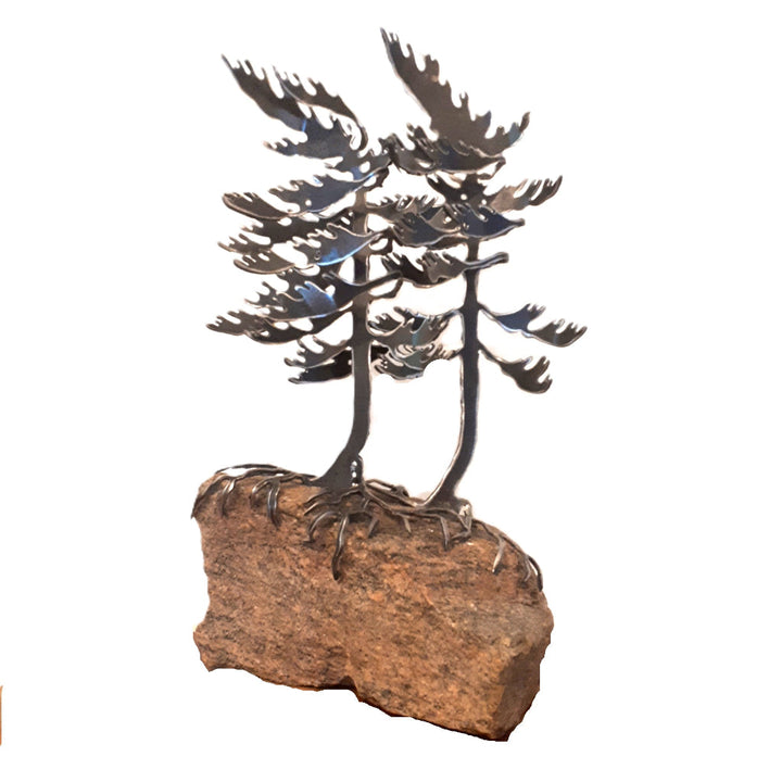Metal sculpture of two white pine trees on a rock base 