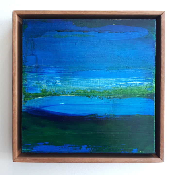 Abstract painting with blue and green hues in a wooden frame on a white background