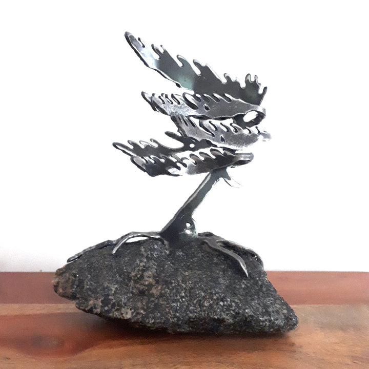 Metallic sculpture of a white pine tree on a piece of granite